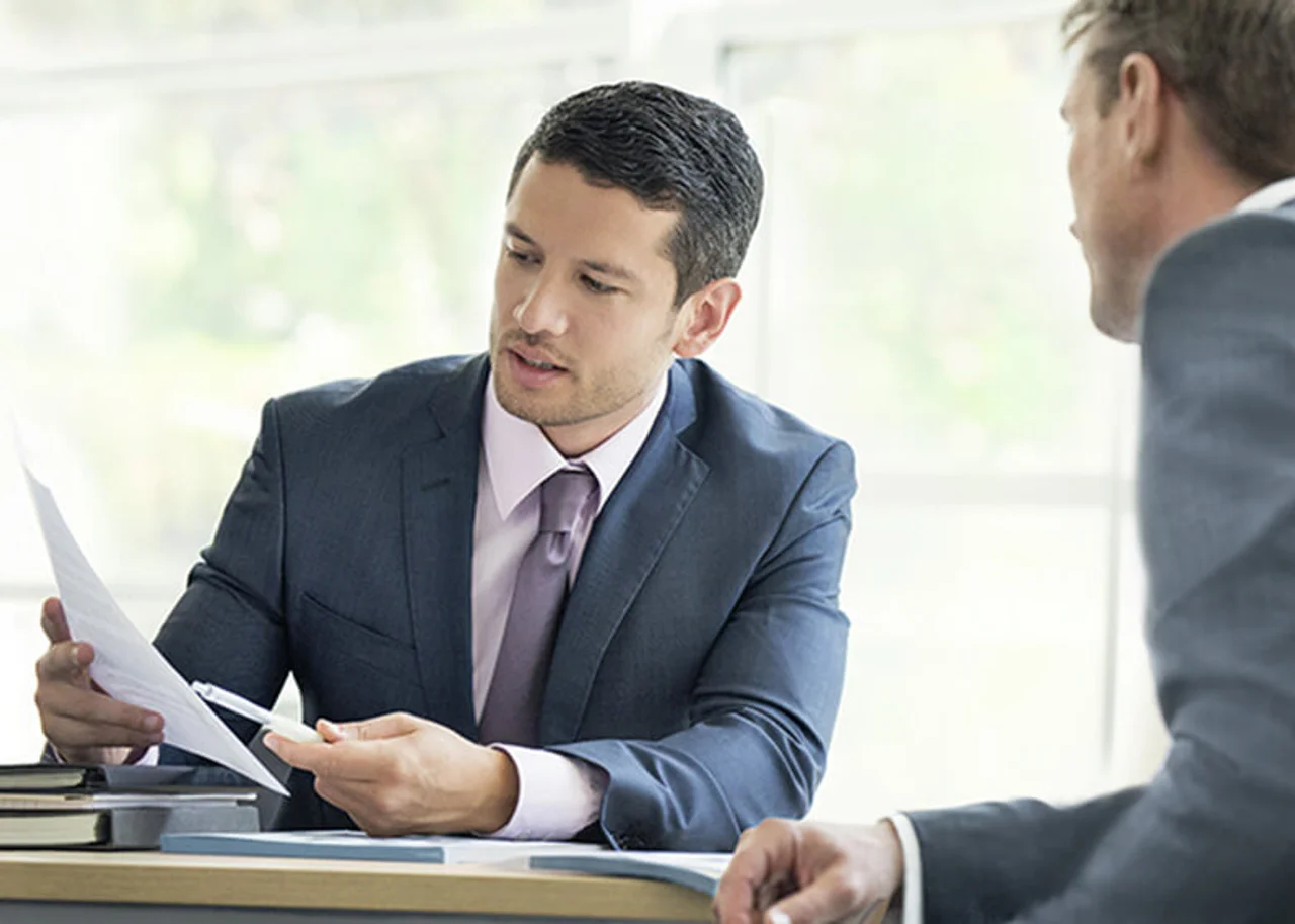 Two men in suits are looking at something on a printout