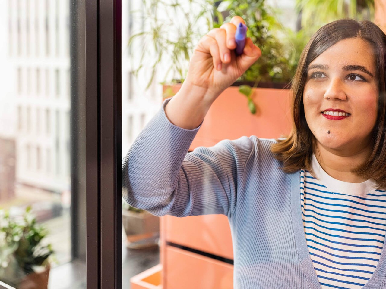 Woman writes her ideas on a glass pane