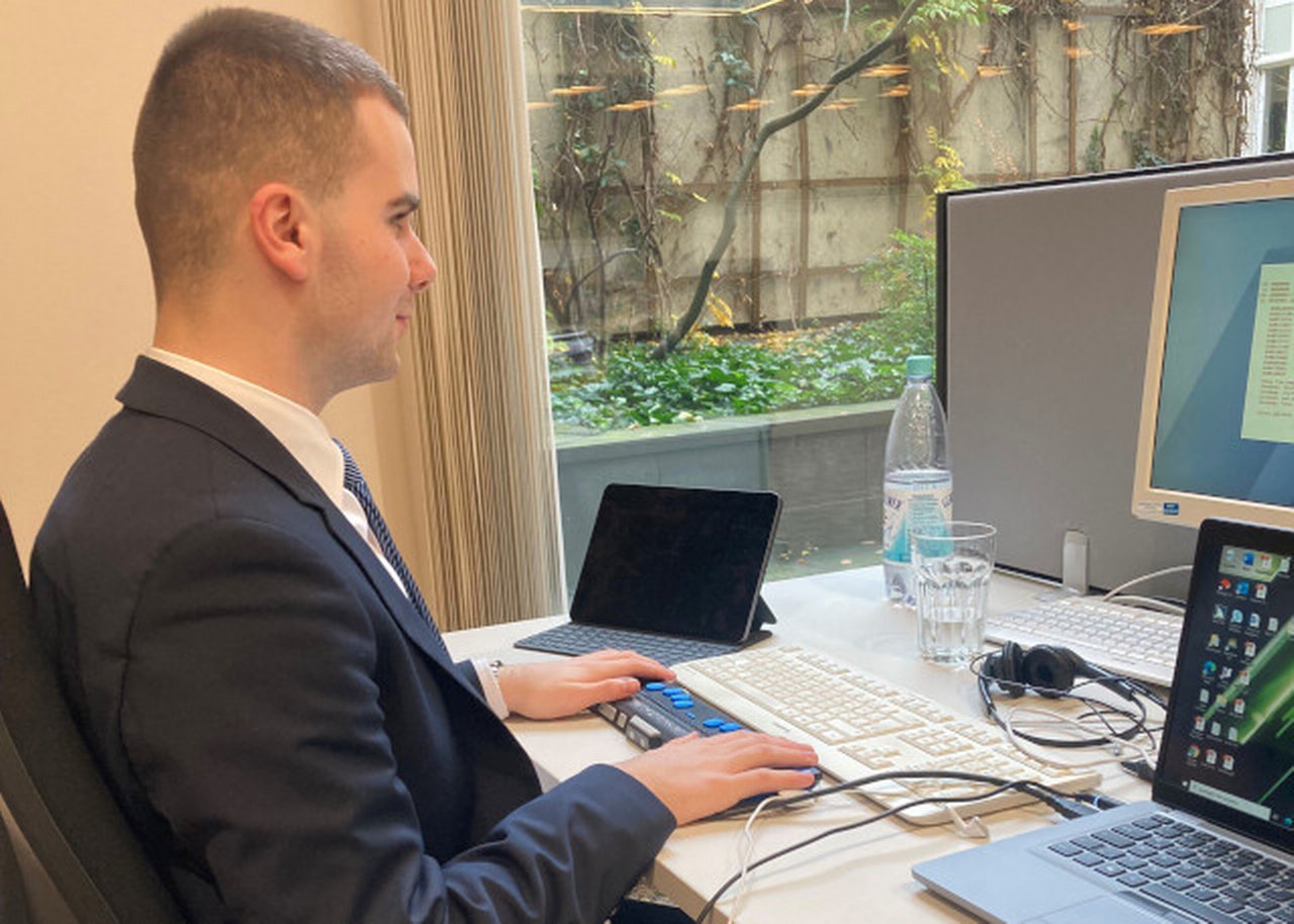 Giuliano sitzt am Schreibtisch vor Laptops und Bildschirmen