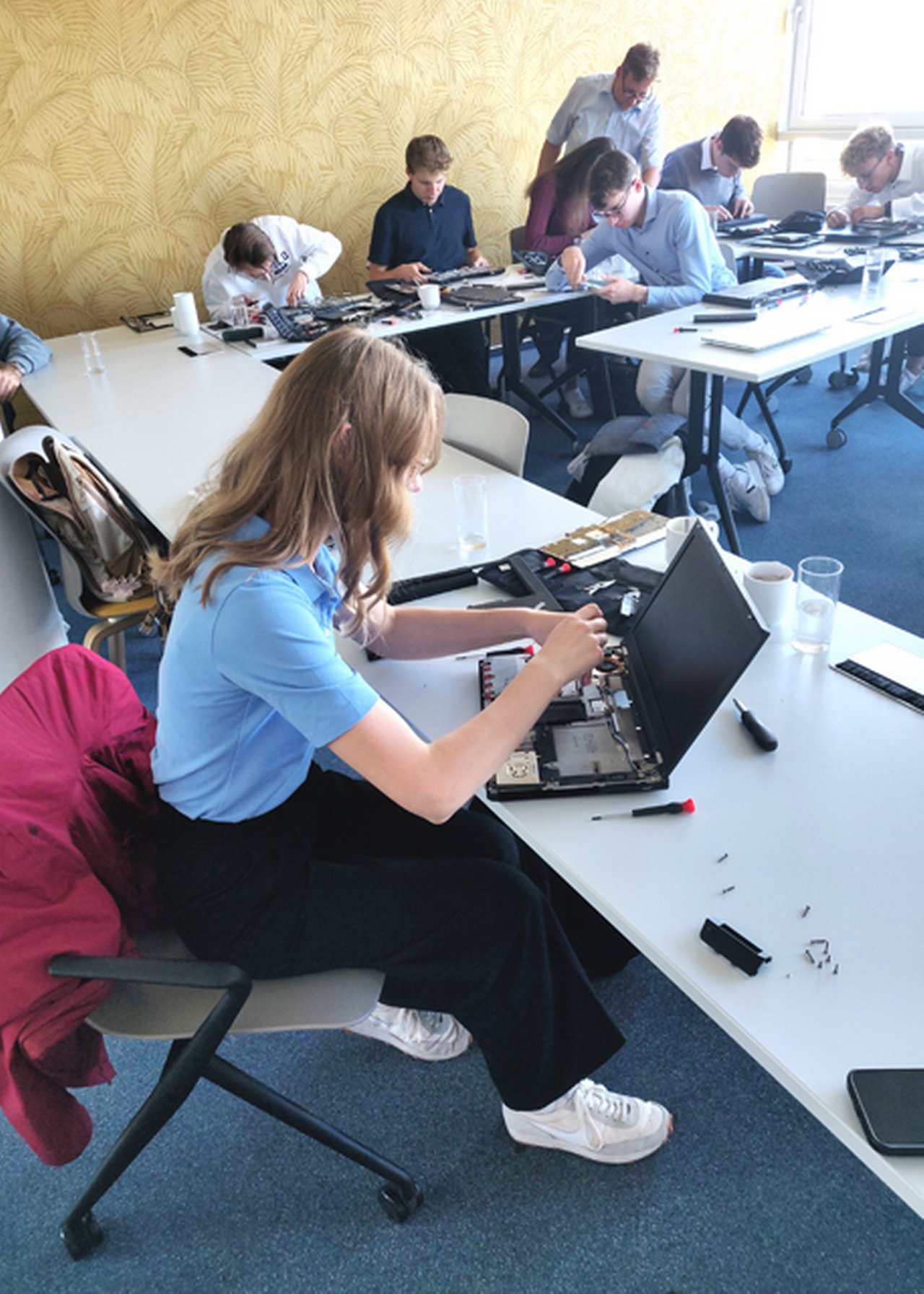Nina schraubt mit Werkzeug an einem Laptop